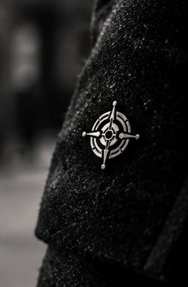 A small GoPlay pin on the lapel of a dark coat